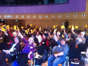 WILPF members vote raise a yellow card to vote for the appoval of the WILPF 2015 Manifesto 