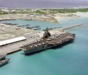 An aerial port bow view of the aircraft carrier USS SARATOGA (CV-60) tied up at pier. This is the first time an aircraft carrier has visited the island.