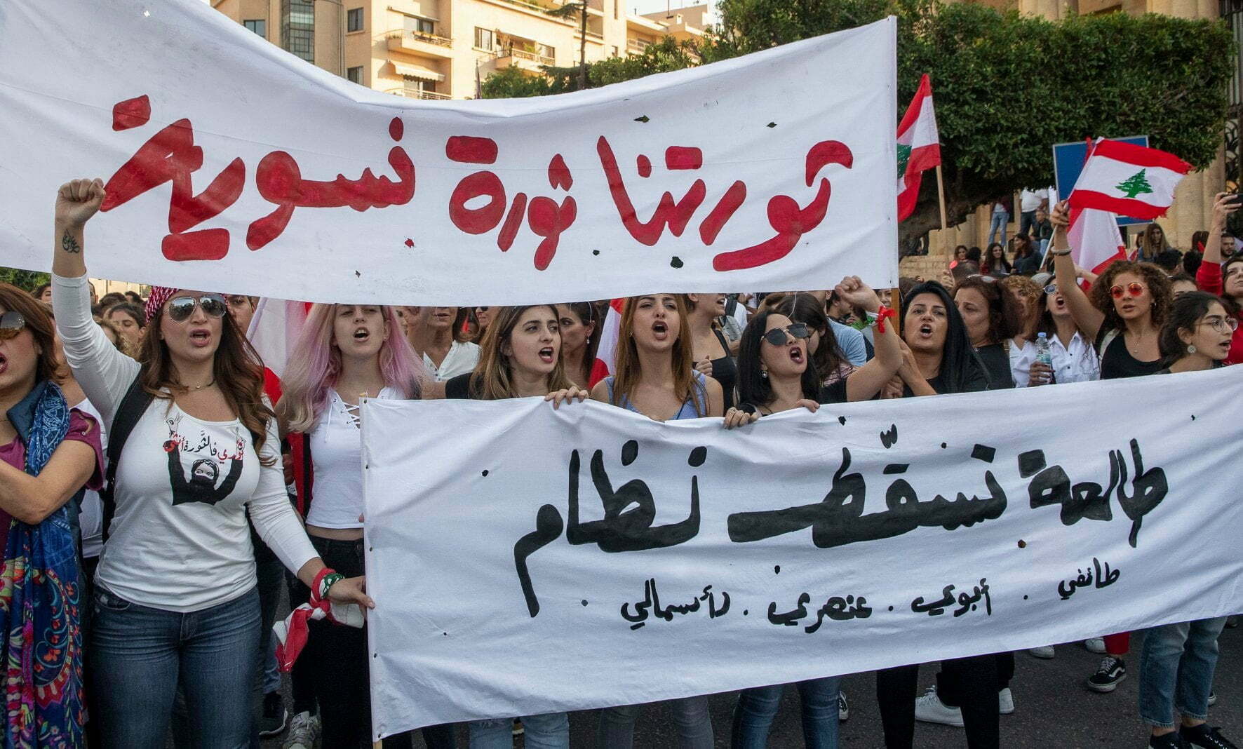 Women marching and holding a white slogan with black letters