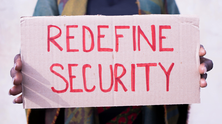 Woman holding a sign reading "Redefine Security".