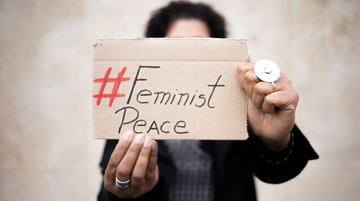 Woman holding a "Feminist Peace" sign