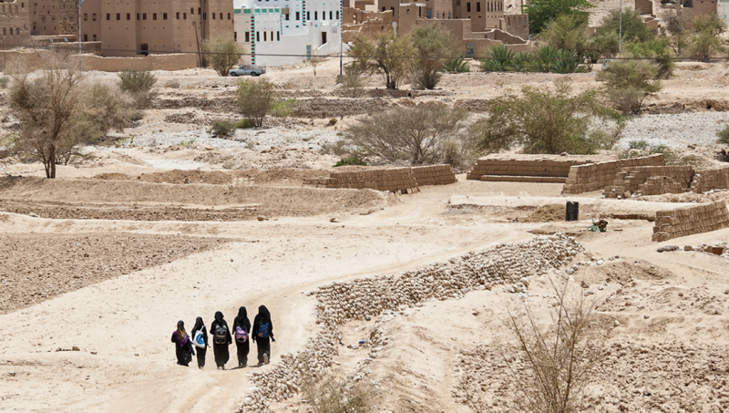 Five veiled women walking in Yemeni desert area