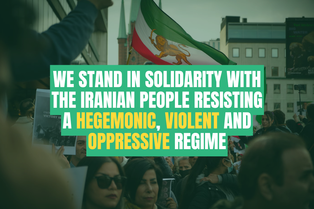 A crowd of people protest, holding signs, with an Iranian flag in the background. Overlaid text reads: We stand in solidarity with the Iranian people resisting a hegemonic, violent and oppressive regime.