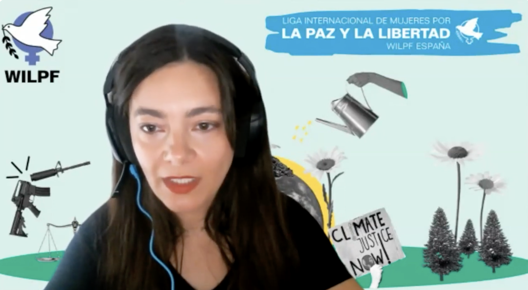 A woman with long brown hair and headphones speaks on a video call. Behind her is a colourful background with peace symbols, flowers, a rifle turning into a flower, and the text “Liga Internacional de Mujeres por la Paz y la Libertad.”.